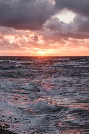 夕陽映照波濤洶湧的海洋，海浪拍打，雲層壯觀。 — 瑞典 壁紙