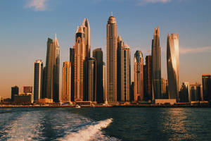 杜拜日落時分的天際線，一艘快艇在水面上留下尾跡。 — 杜拜 壁紙