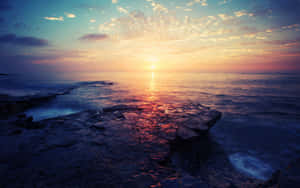 海洋上的夕陽，前景岩石反射溫暖的色彩。 — 最酷的桌面 壁紙