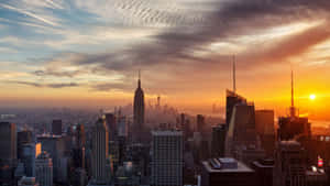 紐約天際線在夕陽下，金色光芒和戲劇性的雲彩。 — 城市風景 壁紙