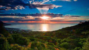 海岸小鎮的夕陽，有綠色山丘和海洋 — 非洲藝術 壁紙