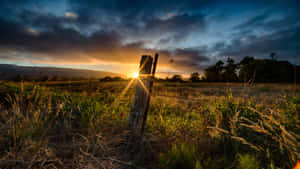 夕陽在草地上籬笆柱後，伴隨著戲劇性的雲彩。 — 農場 壁紙