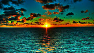 海面上鮮豔的夕陽，伴隨著多彩的雲朵和金色的水面倒影。 — 海景 壁紙
