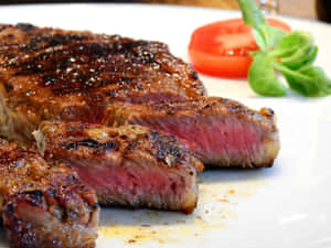切片 medium-rare 牛排搭配番茄和羅勒在白色盤子上。 — 4:3 壁紙