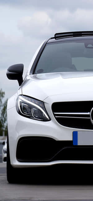 白色 Mercedes-Benz 跑車帶有黑色飾邊，在陰天停放在戶外。 — iPhone 16 壁紙