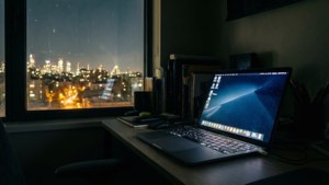 桌子上筆記型電腦，窗外雨夜城市景觀。 — MacBook 動態圖片 壁紙