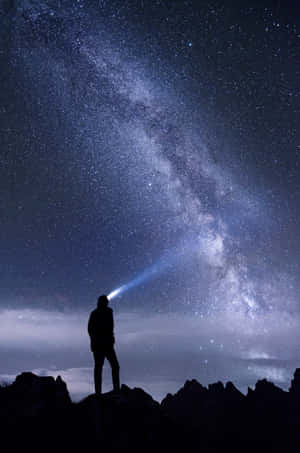 人在山頂上將手電筒照向星空 — 夜空 壁紙