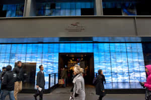 人們夜晚經過一間設有藍色海浪數位顯示屏的Hollister商店。 — Hollister 壁紙