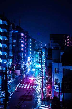 夜晚霓虹燈照亮都市街道，濕漉漉的路面反射出繽紛燈光。 — 城市燈光 壁紙