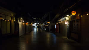 一條安靜的雨夜街道，有發光的燈籠和關閉的商店。 — 鄰里 壁紙