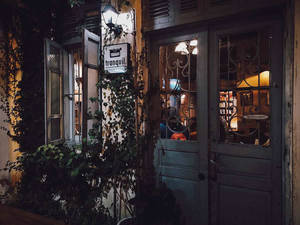 夜晚舒適的復古咖啡店入口，有常春藤和溫暖的室內燈光。 — 河內 壁紙
