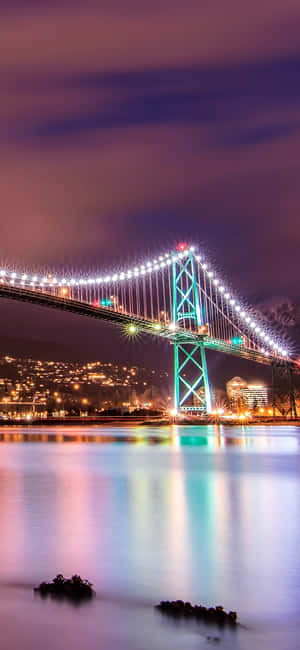 夜晚中明亮照明的吊橋，平靜水面上的倒影和紫色天空。 — 城市 壁紙