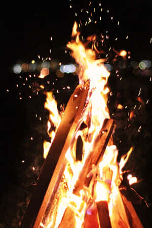 一個充滿活力的營火，火花飛向夜空。 — 2:3 壁紙
