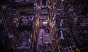 夜晚密集城市景觀的鳥瞰圖，有發光的燈光和高的建築物。 — 昏暗 壁紙