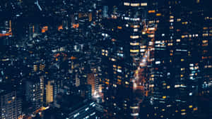 從空中視角看到的夜晚城市景觀，帶有發光的窗戶和明亮的街道。 — 城市燈光 壁紙