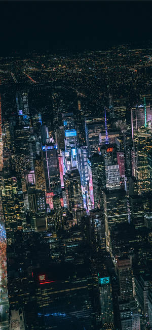 夜晚密集的城市天際線鳥瞰圖，建築物和霓虹燈閃閃發光。 — Galaxy S24 壁紙