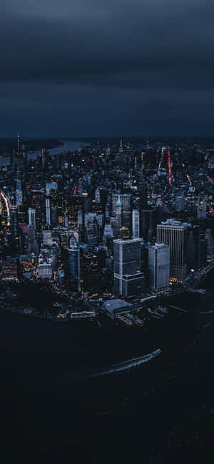 夜間城市景觀，燈火通明的建築物和下方的黑暗水域。 — 紐約 壁紙