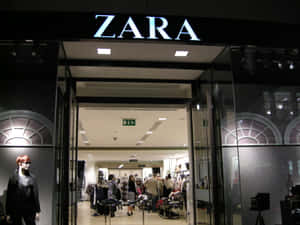 Zara服裝店入口，夜晚店內有顧客，店外有人體模型。 — Zara 壁紙