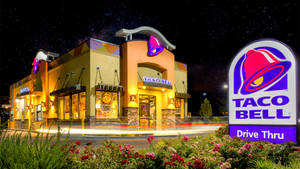 夜晚Taco Bell餐廳亮起燈光，設有得來速招牌和星空。 — 塔可 壁紙