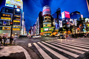 夜晚繁忙的東京街道，有發光招牌和濕漉漉的斑馬線。 — 街頭 壁紙