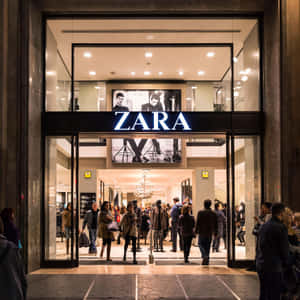 夜晚的Zara店舖入口，購物者進出。 — iPad Pro 12.9 壁紙