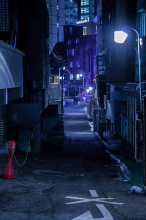 夜晚狹窄的城市小巷，由街燈照亮，遠處有紫色霓虹燈招牌。 — 街頭 壁紙