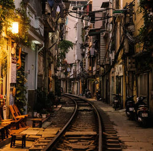 夜晚城市小巷，有鐵路軌道和暖燈下停泊的機車。 — 河內 壁紙