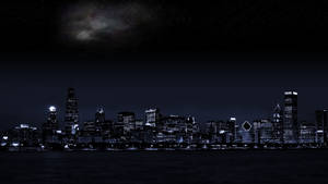夜晚城市天際線，燈火通明的建築物與水面上方的銀河。 — 月亮與星星 壁紙