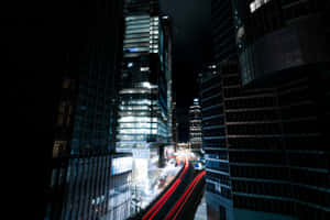 夜晚高聳的城市建築，帶有移動汽車的紅色光條。 — 光線 壁紙