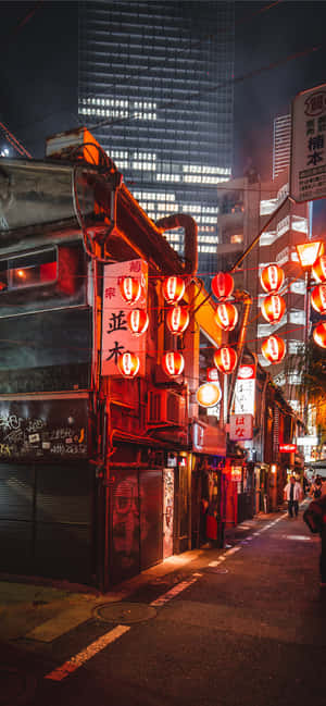 夜晚的東京狹窄小巷，被紅燈籠和霓虹燈照亮。 — iPhone 16 壁紙