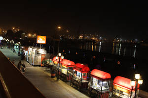 夜市美食車沿水邊排列，水中倒影。 — 喀拉蚩 壁紙