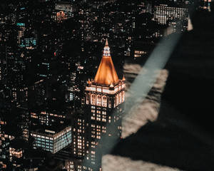 夜間城市景觀，一座突出的發光摩天大樓帶有金色圓頂。 — 城市風景 壁紙