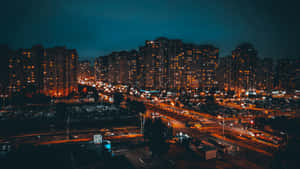 夜間城市景觀，燈火通明的建築和流動的交通。 — 城市燈光 壁紙