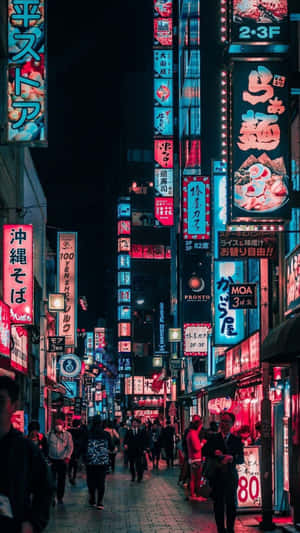 夜晚霓虹燈照亮的東京街道，有發光的招牌和行人。 — 日本 壁紙