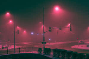 夜晚紅色燈光照亮的積雪街道十字路口，有霧和交通燈。 — 淺色 壁紙