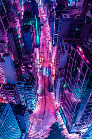 夜晚充滿活力的霓虹燈城市街道鳥瞰圖，周圍環繞著高樓大廈。 — 城市燈光 壁紙
