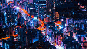 一個充滿活力的夜晚城市，有發光的高速公路和燈火通明的摩天大樓。 — 日式 壁紙