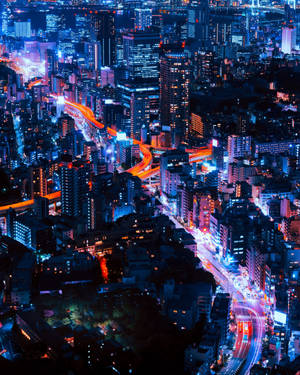 充滿活力的城市夜景鳥瞰圖，有發光的藍色建築物和交通的橙色光跡。 — 城市風景 壁紙