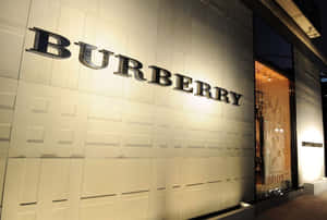 夜間 Burberry 商店外牆，帶有發光標誌和帶紋理的牆板。 — Burberry 壁紙
