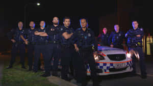 一群警察在夜間站在巡邏車附近。 — 警察 GIF 壁紙