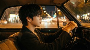 年輕男子在夜間駕駛復古車穿過城市，燈光模糊