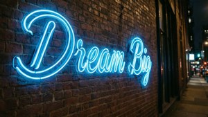 夜晚磚牆上寫著 Dream Big 的藍色霓虹燈牌。 — 霓虹藍美學 壁紙