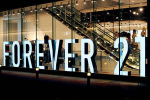 夜晚明亮的Forever 21商店招牌，內部可見電扶梯和模特兒。