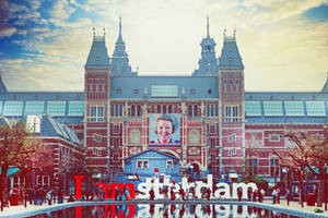 阿姆斯特丹博物館，有巨型肖像和I amsterdam標誌，有人群和水面倒影。 — 阿姆斯特丹 壁紙