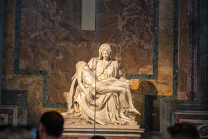 大理石 Pietà 雕塑，瑪利亞懷抱耶穌，在博物館展出，下方有遊客。 — 美學大理石 壁紙