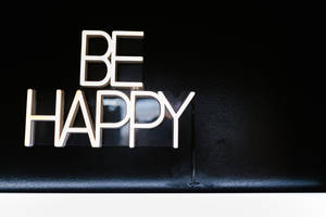 黑色紋理表面上的金屬「BE HAPPY」字母 — 霓虹燈 壁紙