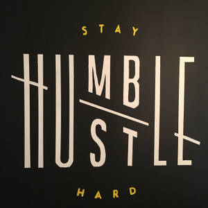 勵志文字牆藝術，以大膽的白色和黃色字體寫著「Stay Humble Hustle Hard」。 — 名言 壁紙