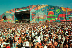 Woodstock 99音樂節人群面向色彩繽紛的舞台，背景是清澈的藍天。 — Woodstock 壁紙