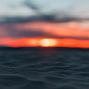 沙丘上的日落，帶有橙色光芒和柔和的雲彩 — 光線 壁紙