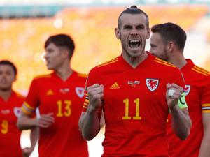 威爾斯足球員加雷斯貝爾在陽光明媚的球場上握緊拳頭慶祝勝利。 — 克里斯汀·貝爾 壁紙